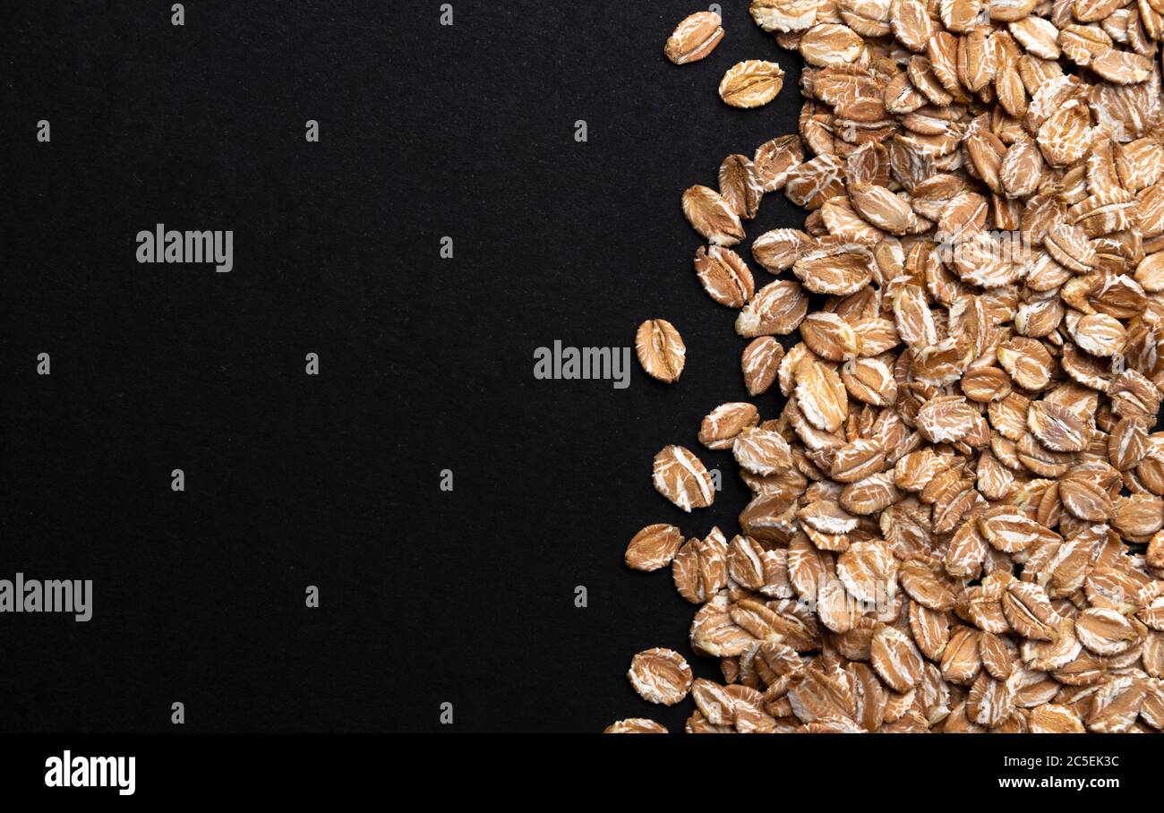 Rye flakes on black background, top view Stock Photo