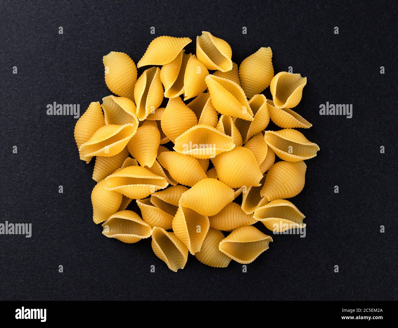 Conchiglie rigate. Raw striped shell pasta on black background, top view Stock Photo