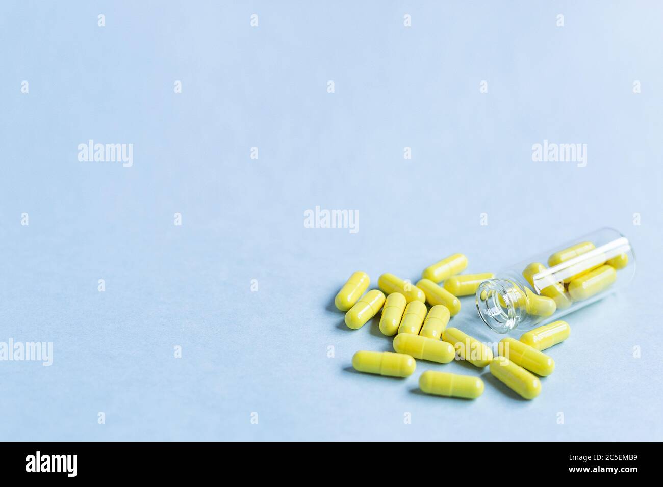 Yellow capsules are poured out of a bottle on a blue background. Omega-3 vitamins. food Supplement. Fish oil in capsules. Free space. space for text. Stock Photo