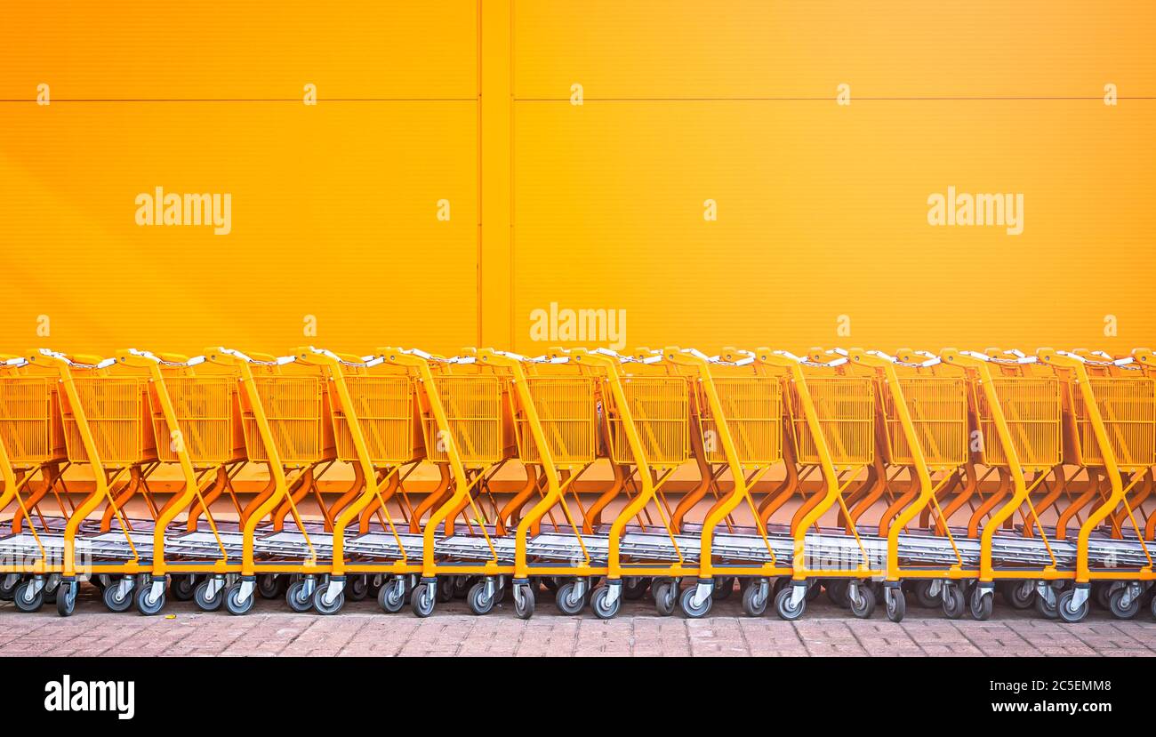 Orange shopping cart stacked by the entrance for new customers to use outside the store orange wall Stock Photo