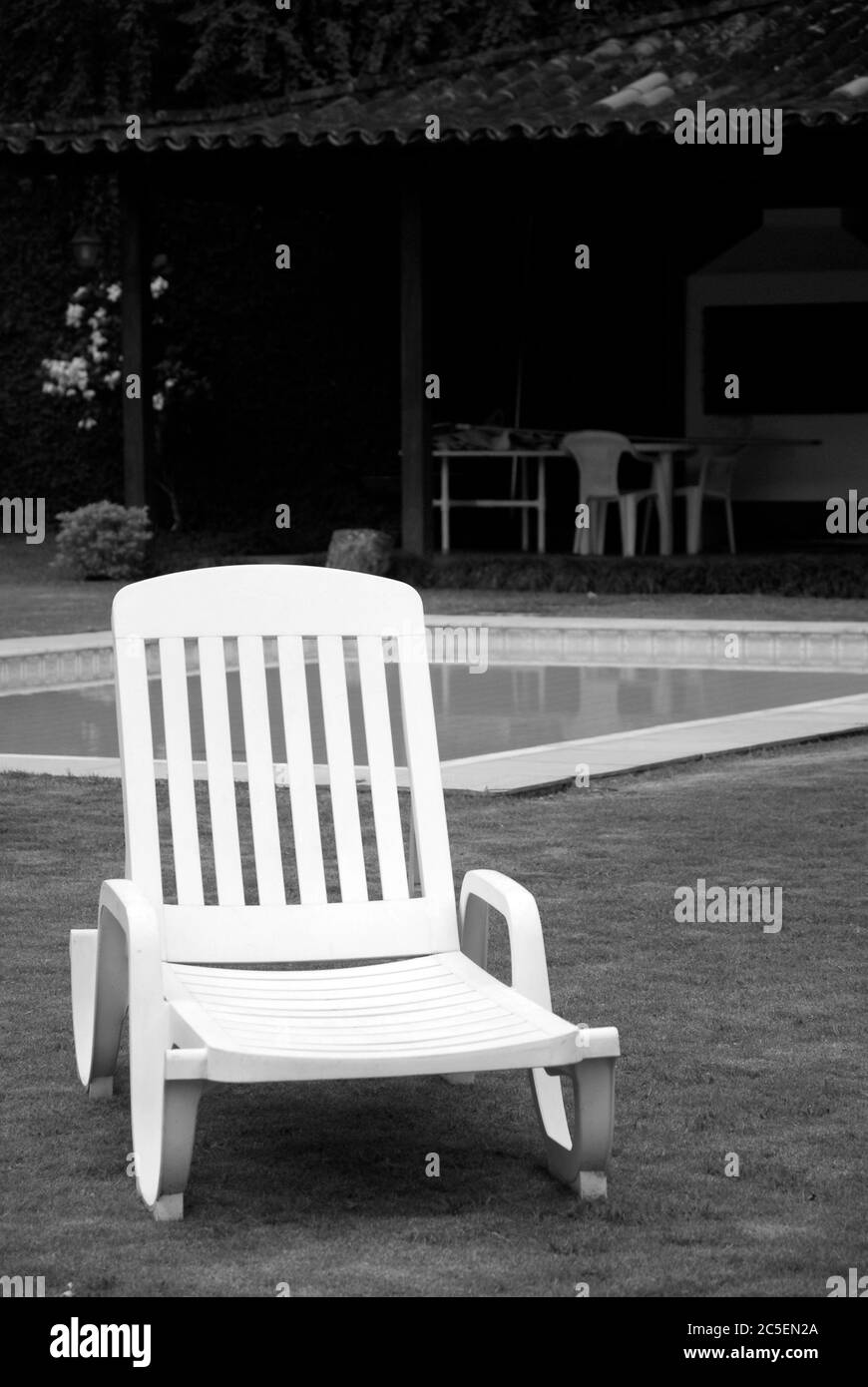 PVC deck chair on lawn with pool and barbecue in the background, Itaipava, Rio de Janeiro, Brazil Stock Photo