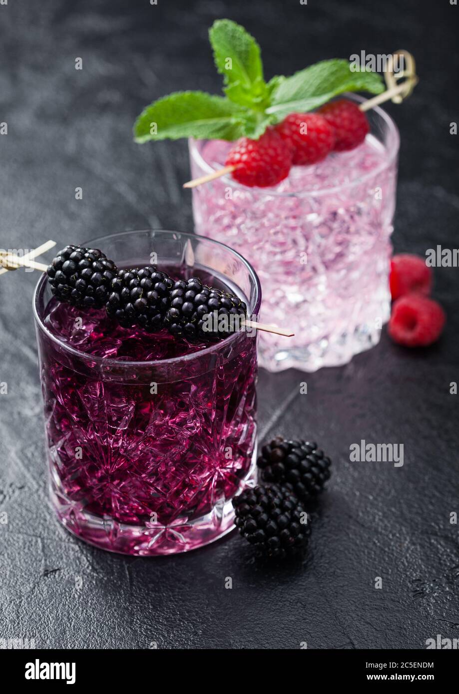 Summer cocktail with blackberry and pink lemonade in crystal glasses with ice cubes and mint on black background.  Soda and alcohol mix. Macro Stock Photo