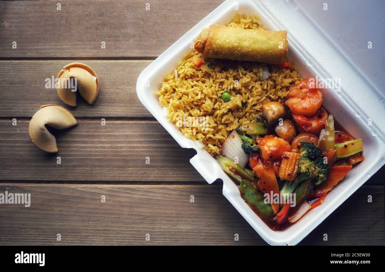 A container of Chinese takeout food on a wooden table Stock Photo