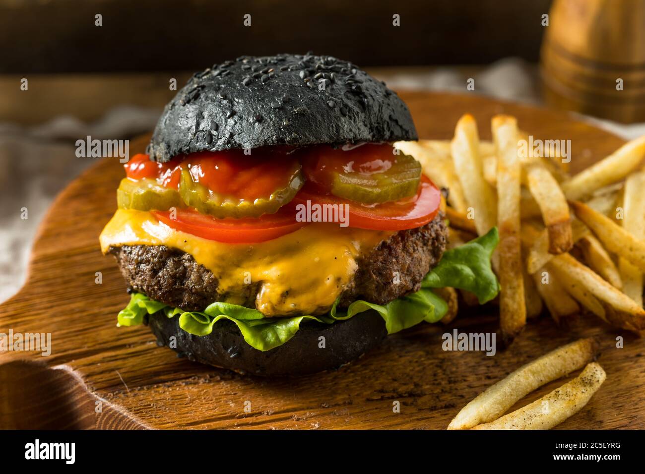 Homemade Cheeseburger with a Black Charcoal Bun and Fries Stock Photo
