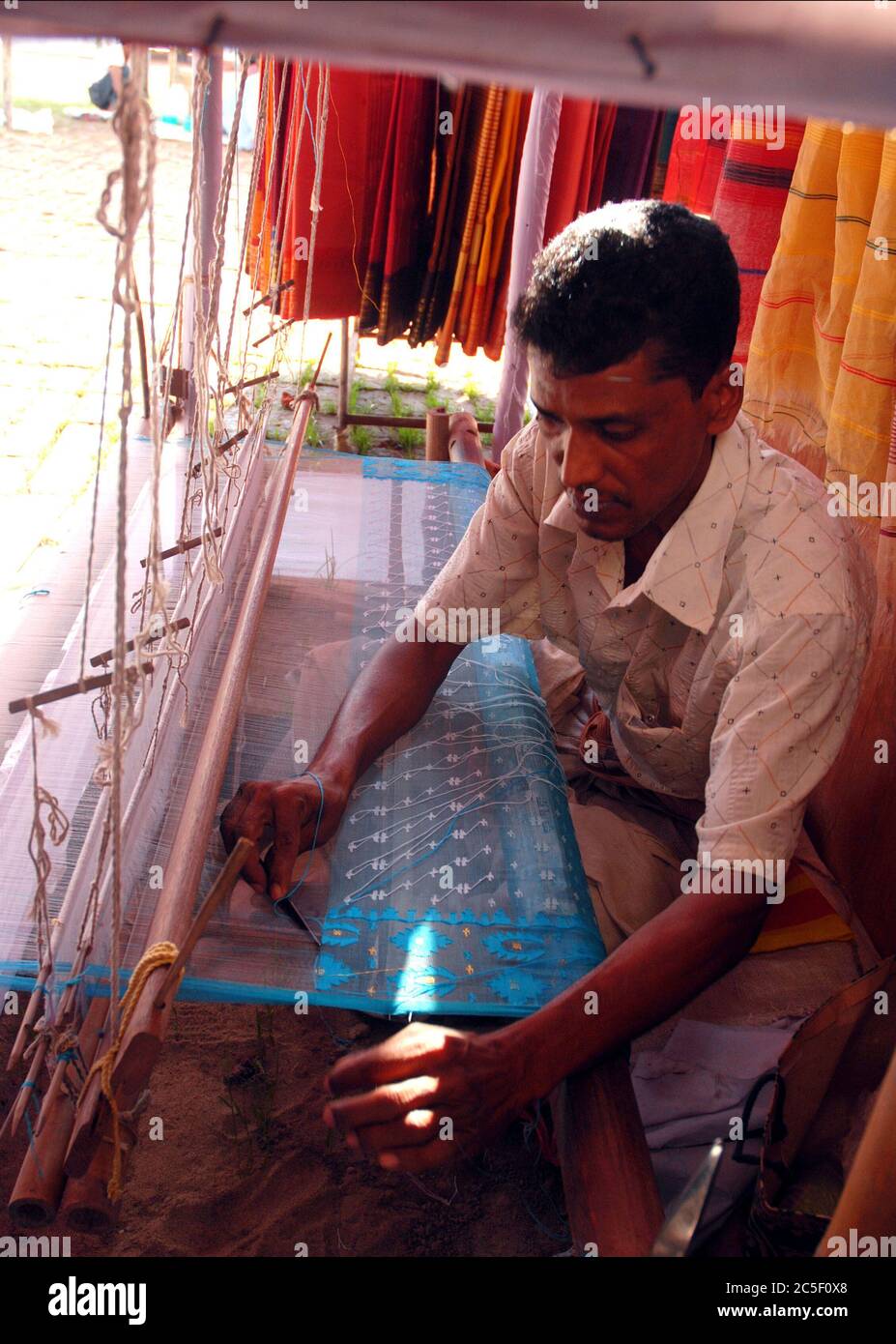A weaver locally known as ‘Tanti’ weavs Jamdani saree, a popular women’s clothing, at  the Women’s fair in Chittagong. Jamdani is a superfine handloom Stock Photo