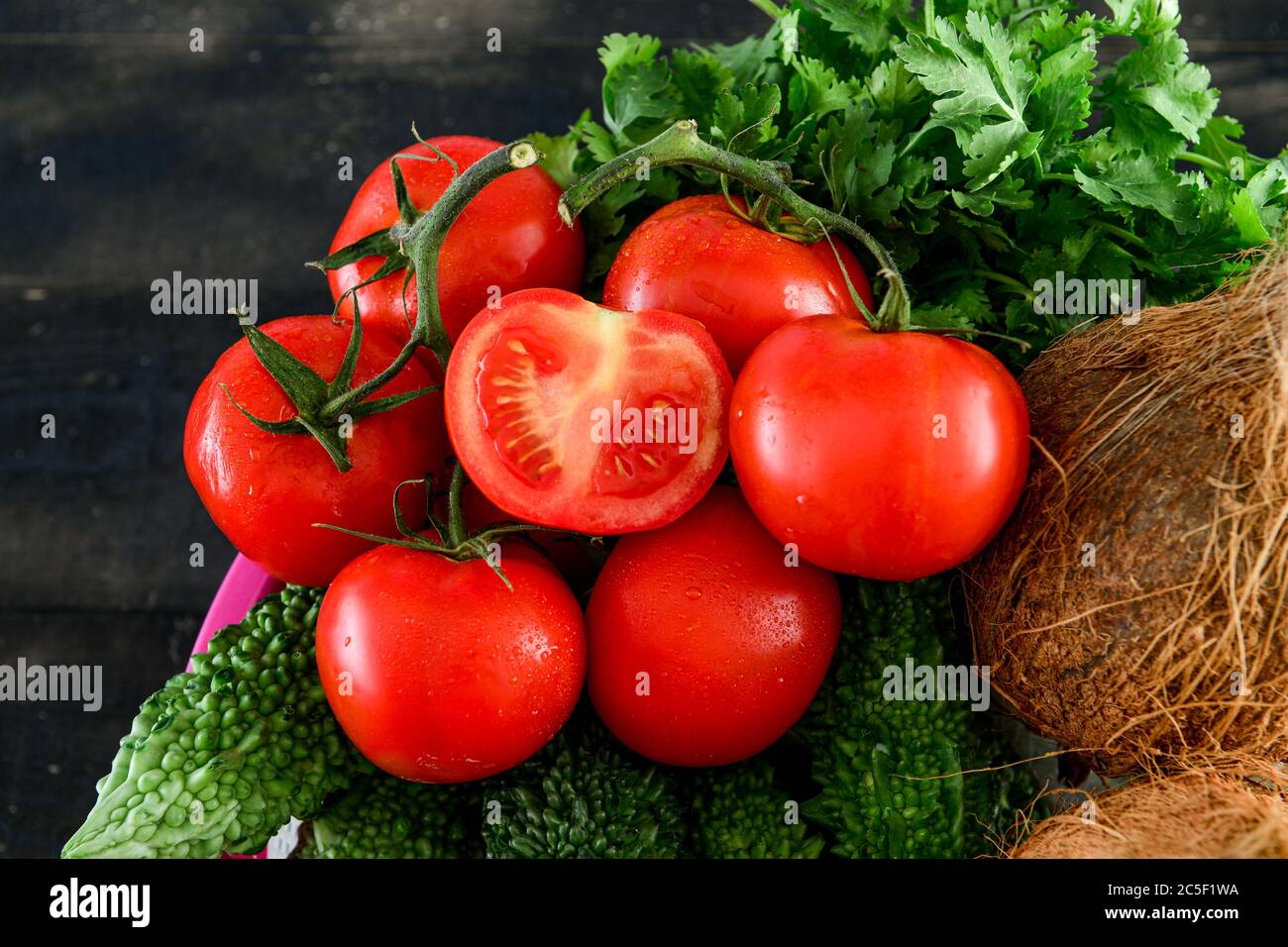 mix Vegetable .tomato, Quora ,karela, in basket on black wooden table Stock Photo