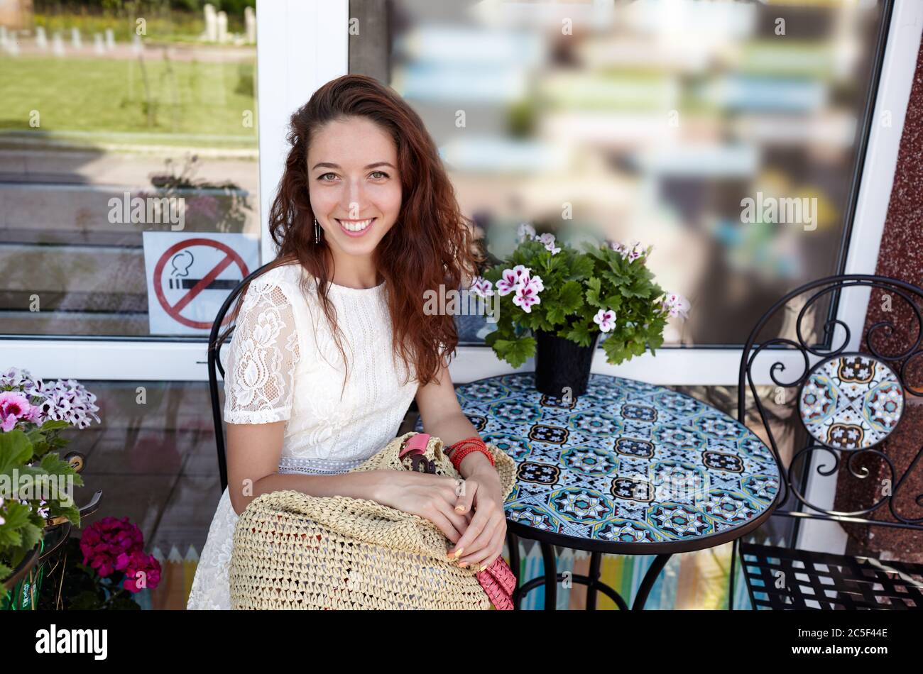 Beautiful attractive woman sit in a cafe and waiting for beverage. Coffee break. Caucasian girl enjoys a bright summer lifestyle Stock Photo