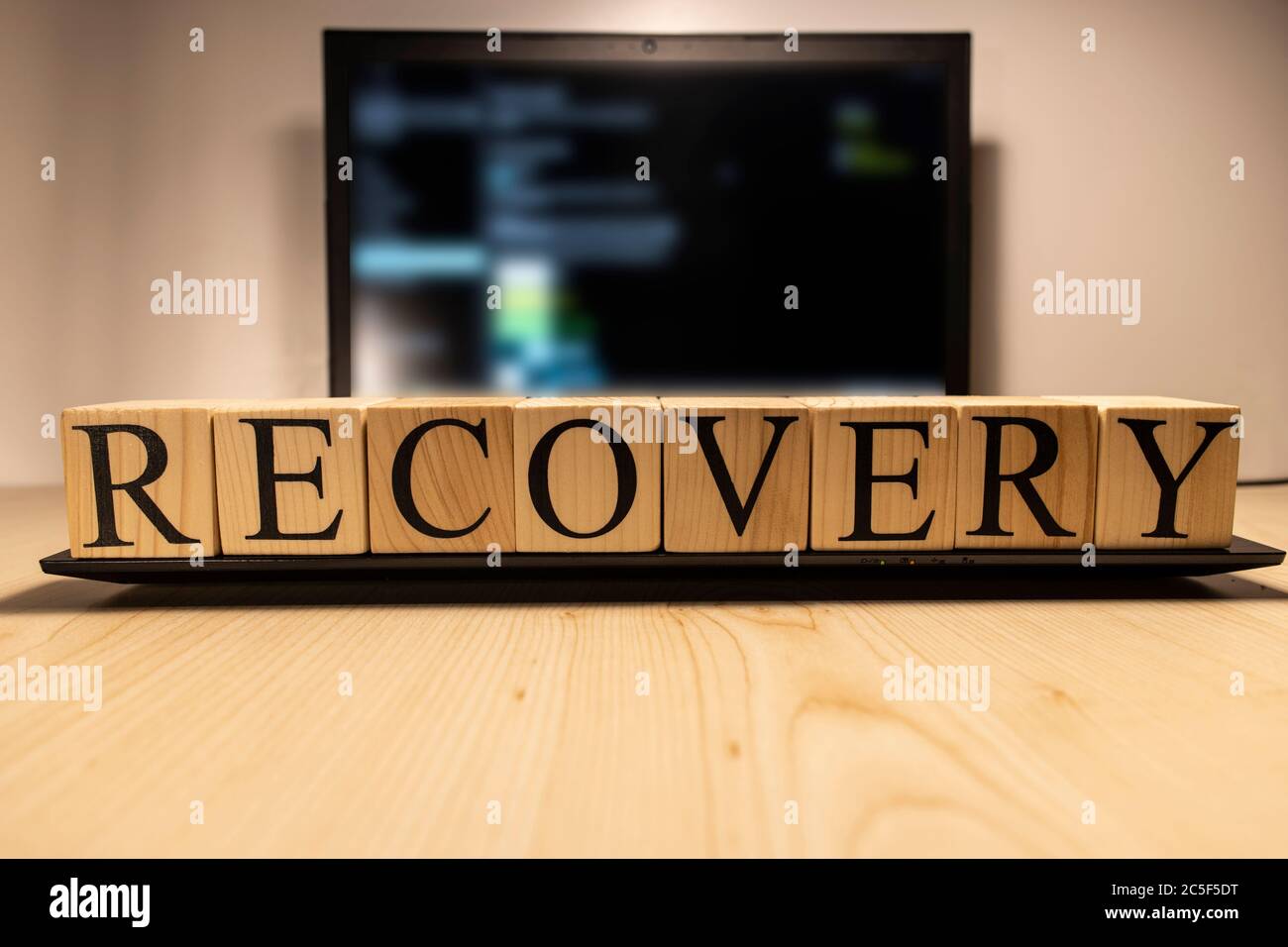 Recovery word from wooden cubes on laptop. Stock Photo