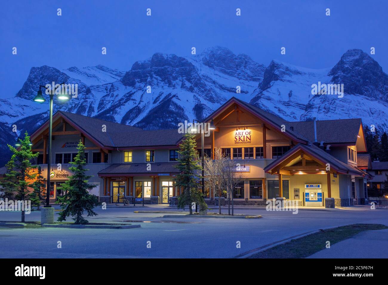 Shops In Canmore On Railway Avenue Alberta Canada At Night With The Snow Covered Mount Rundle Rocky Mountains In The Background Stock Photo