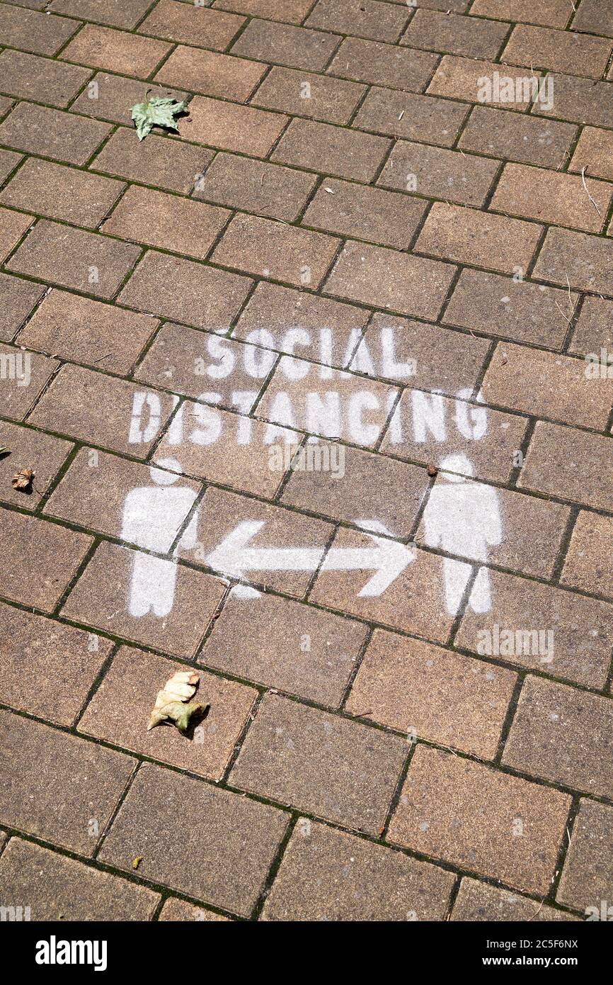 Social distancing reminder stencilled on pavement in white paint Stock Photo