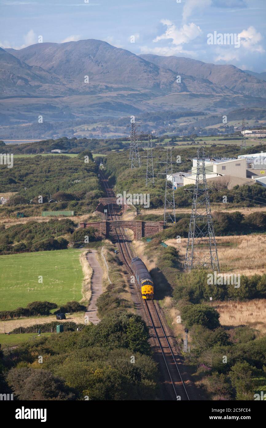 DRS class 37 locomotive 37401 on the rear of a Northern Rail passenger train heading in to the Cumbrian countryside as it departs Barrow In Furness Stock Photo