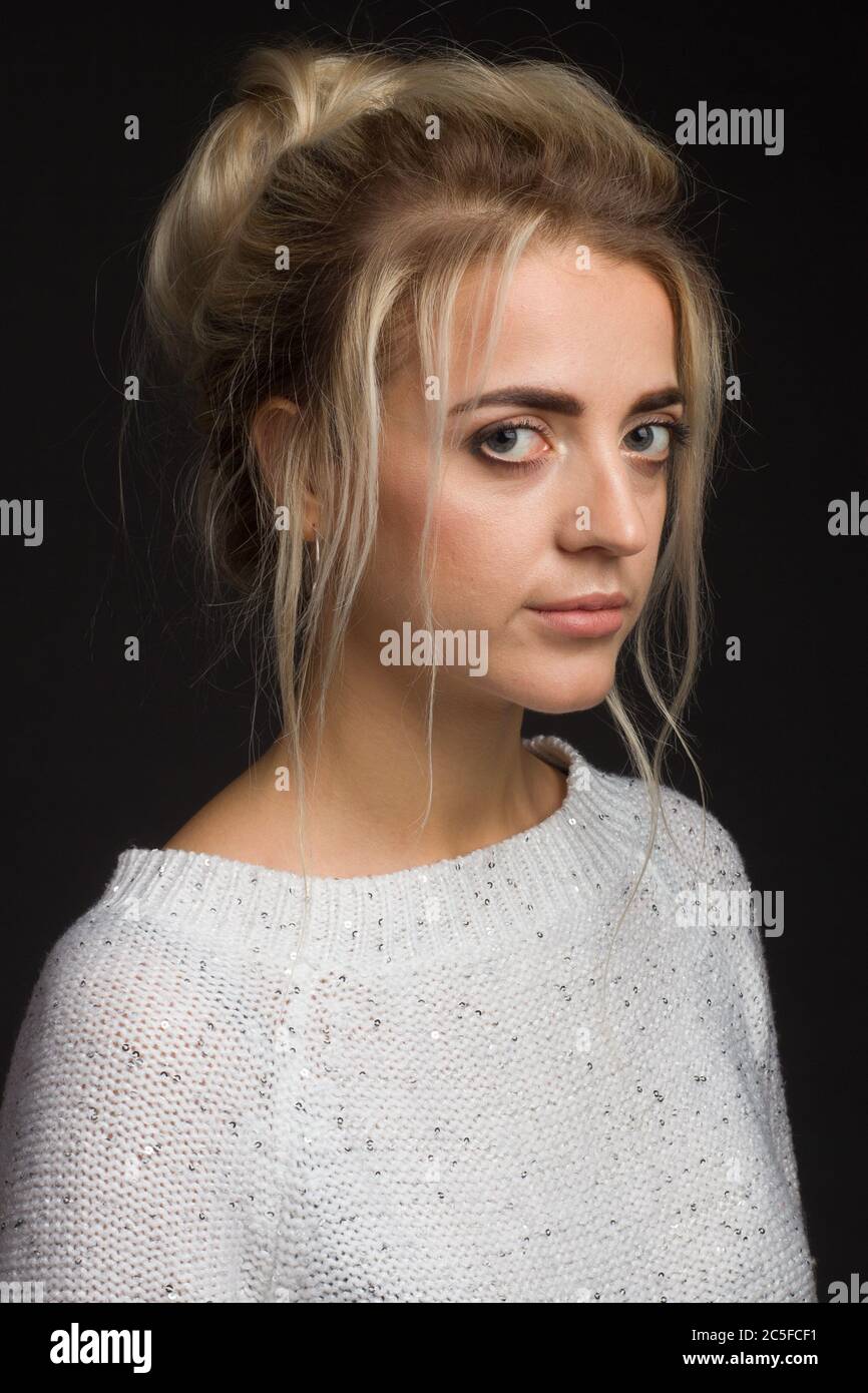 portrait of a blonde with a high hairstyle gulka on a black background in a white sweater Stock Photo