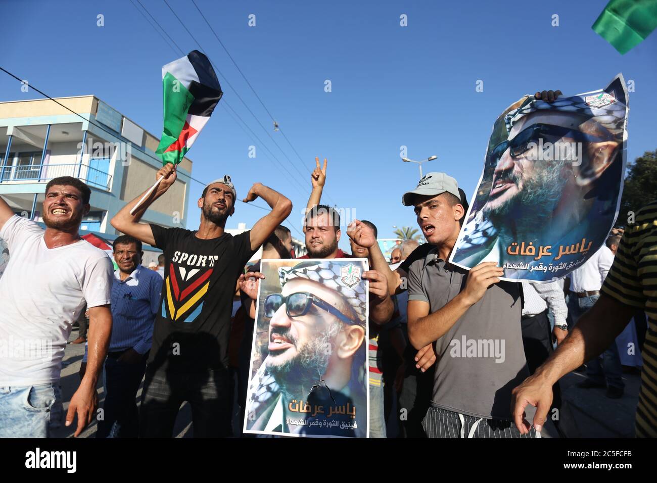 Demonstrators chant slogans while carrying placards of the late Palestinian President Yasser Arafat during a demonstration against Israeli plans to annex parts of the occupied West Bank in the central Gaza Strip. Stock Photo