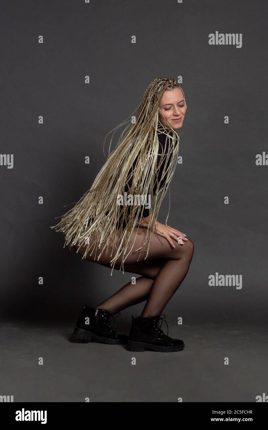 Fashion studio shoot woman . with a creative colorful hairstyle in the form of a pigtail braided from dreadlocks Afro-pigtails in the technique of zizi. in motion air dancing Stock Photo