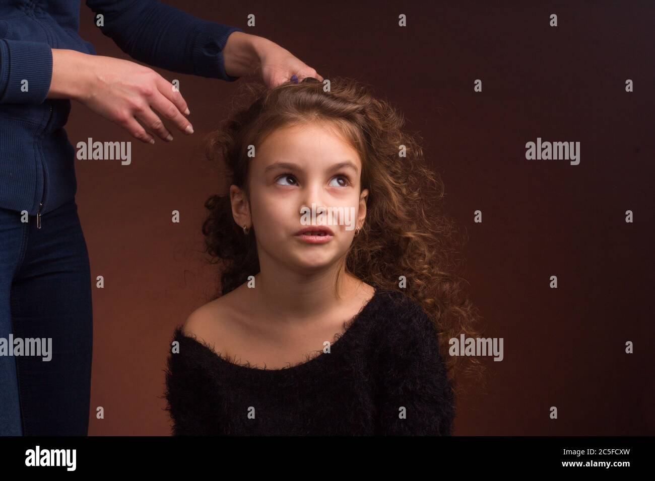 Studio portrait of a little girl, with a disgruntled face and curly