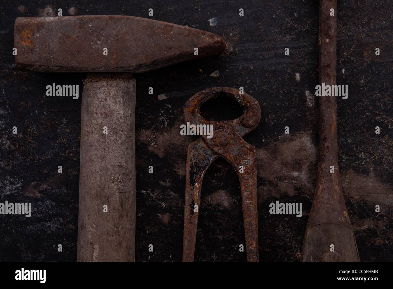 old tools, hammer, chisel, spatula measuring tape and brushes greasy and dirty heavily rusted lie on a metal dark background Stock Photo