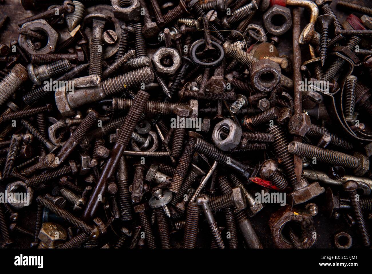 old nuts screws and nails greasy and dirty heavily rusted lie on a metal dark background 2C5FJM1