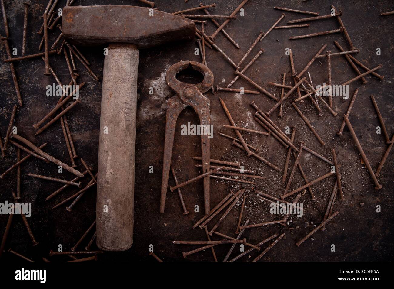 old tools hammer, pliers and nails heavily rusted lie on a metal dark background Stock Photo