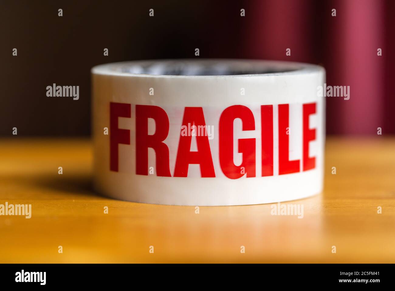 A roll of 'Fragile' warning sticky tape - the word fragile printed in red letters Stock Photo