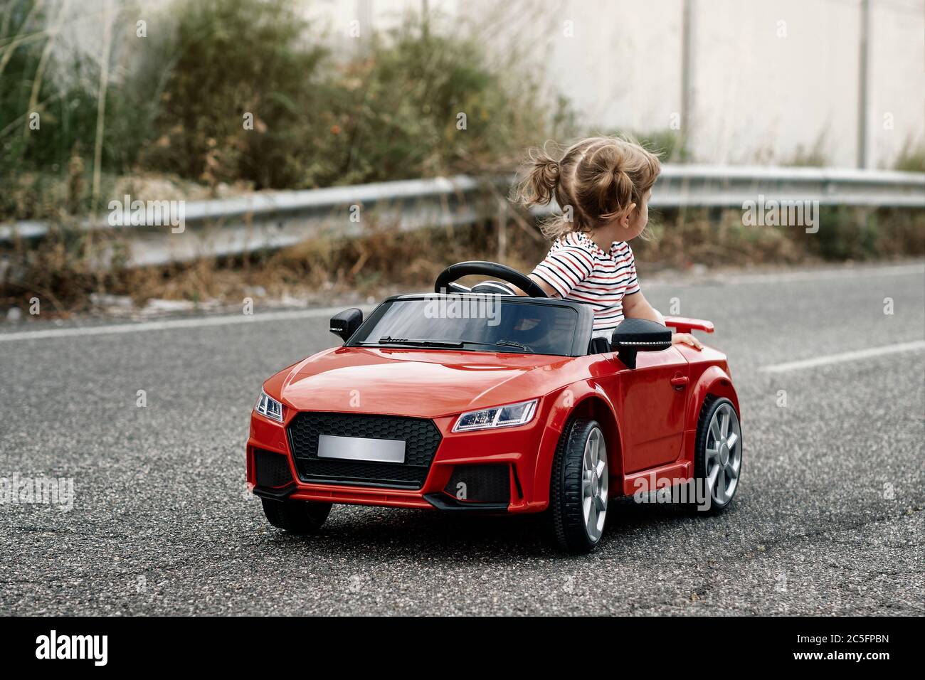 An 18-month-old girl riding in a red toy car Stock Photo - Alamy