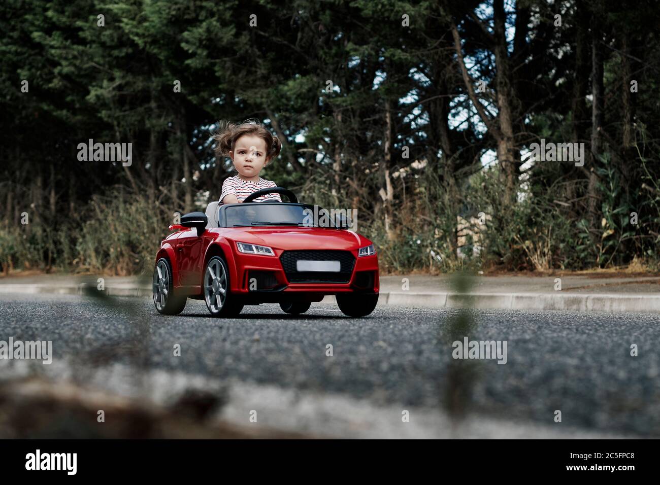 An 18-month-old girl riding in a red toy car Stock Photo - Alamy