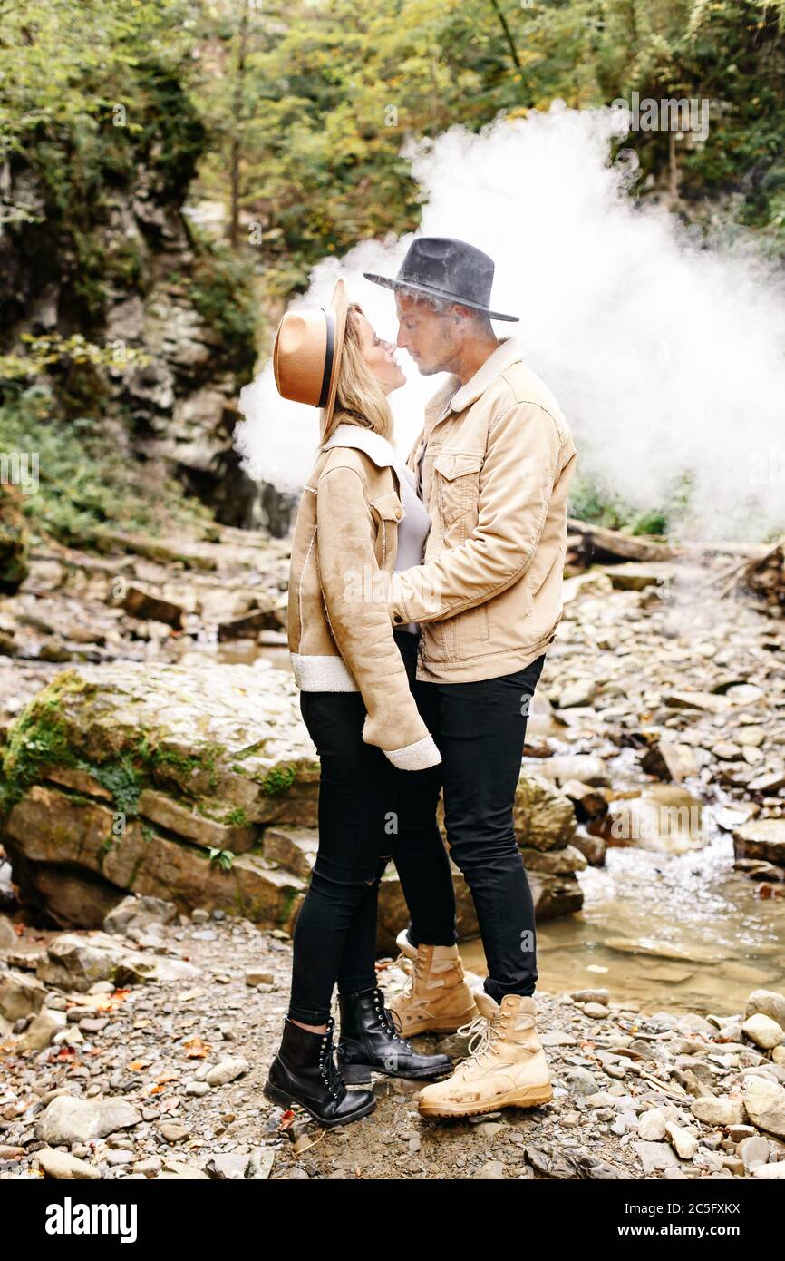 Couple in vape cloud. Two in smoke. Tourists in cold autumn forest with vape. Man and women in smoke. Two smokers. Beautiful couple in fog. E-cigarett Stock Photo