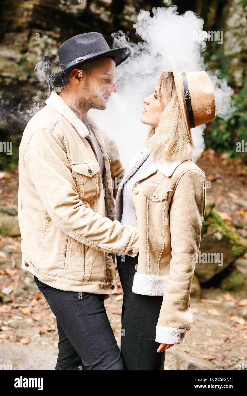 Couple in vape cloud. Two in smoke. Tourists in cold autumn forest with vape.  Man and women in smoke. Two smokers. Beautiful couple in fog. E-cigarett  Stock Photo - Alamy