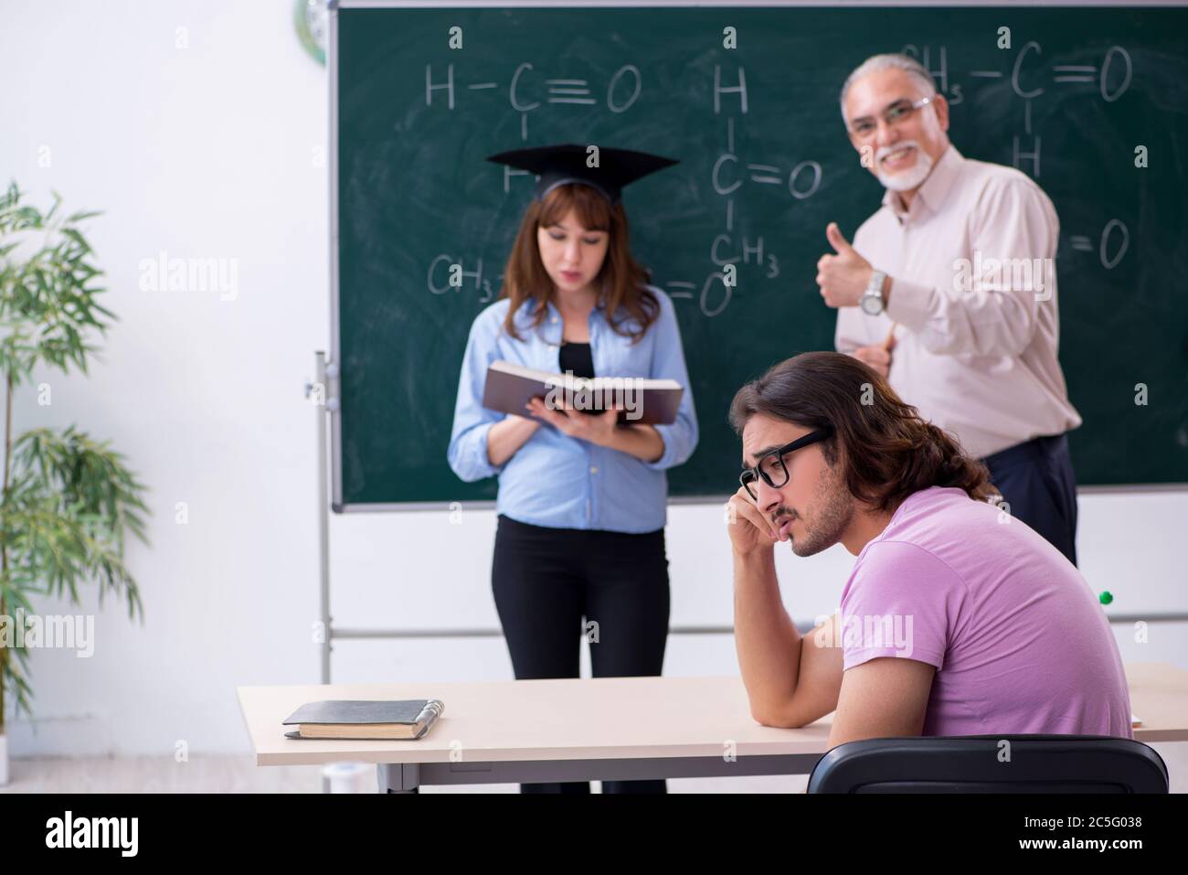 Old teacher and two students in the classroom Stock Photo - Alamy
