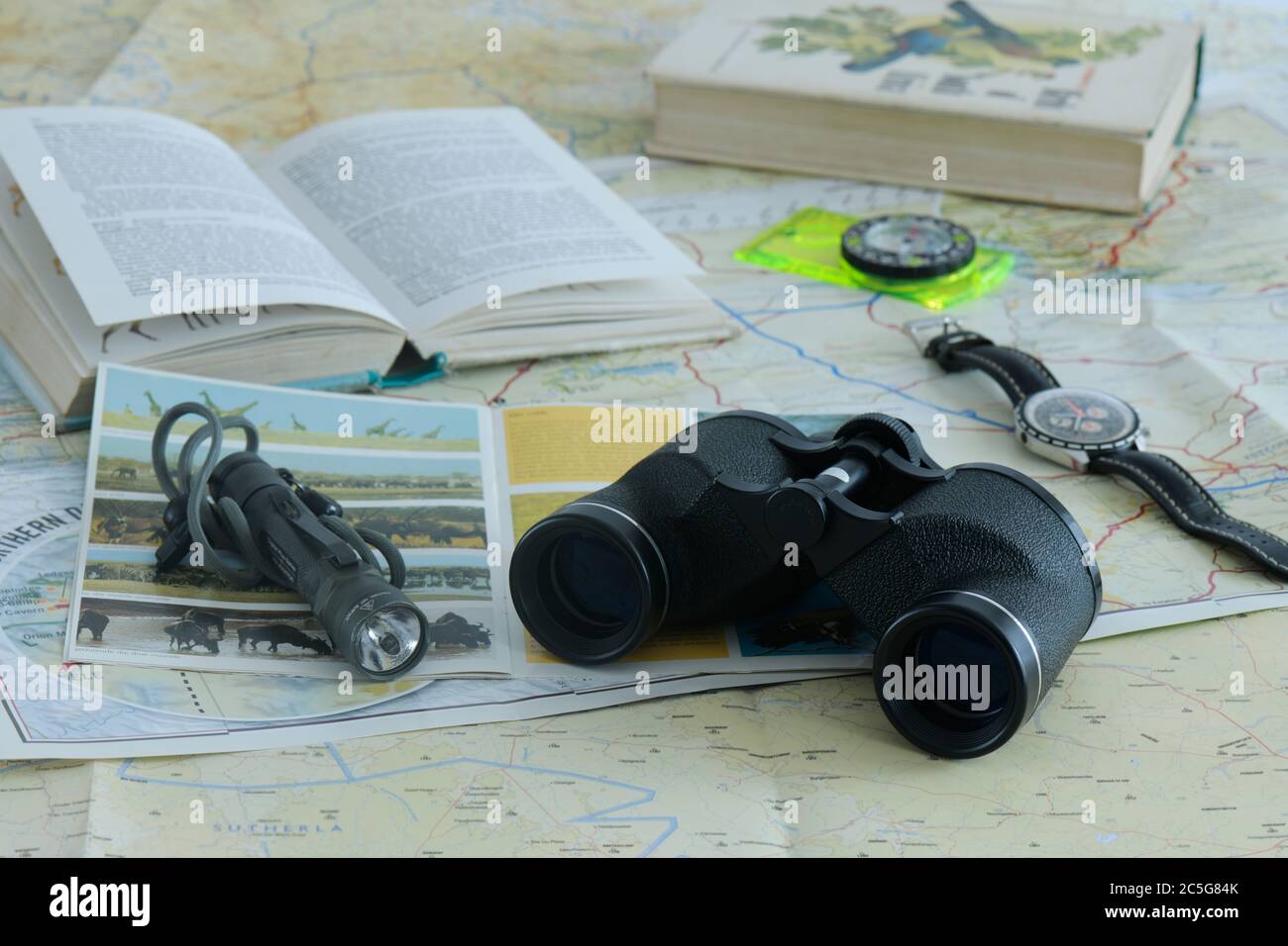 Planning travel adventure, concept illustration, safari, books, binoculars, watch, flashlight, maps, close up, objects, strategy, preparation, plan Stock Photo