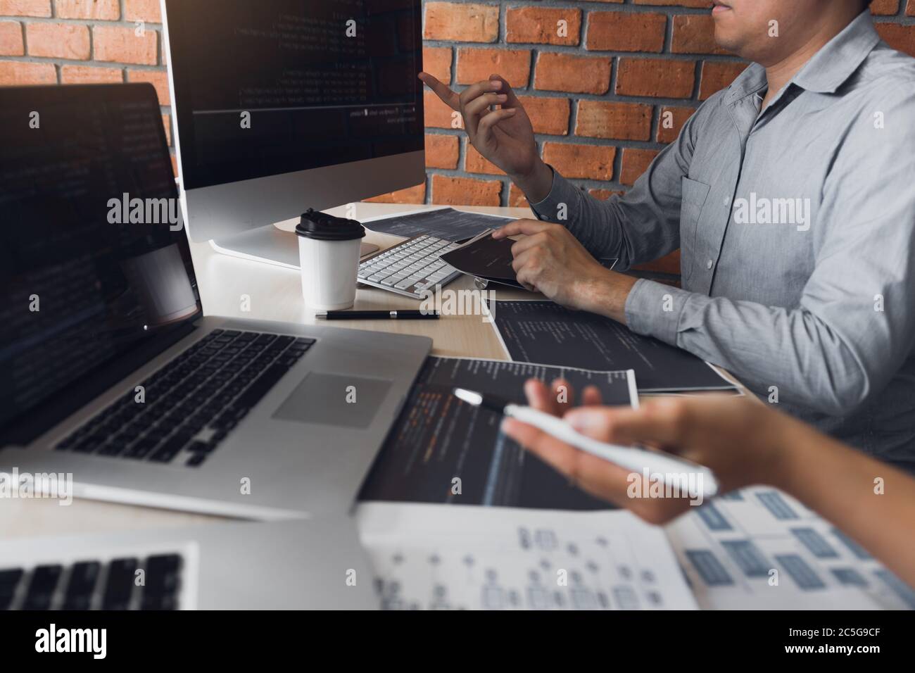 Two software developers are analyzing together about the code written into the program on the computer. Stock Photo