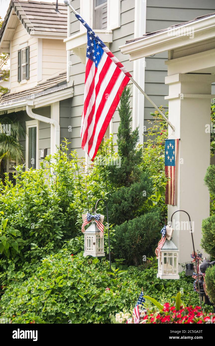 An American flag hanging from a home on the 4th of July; city of