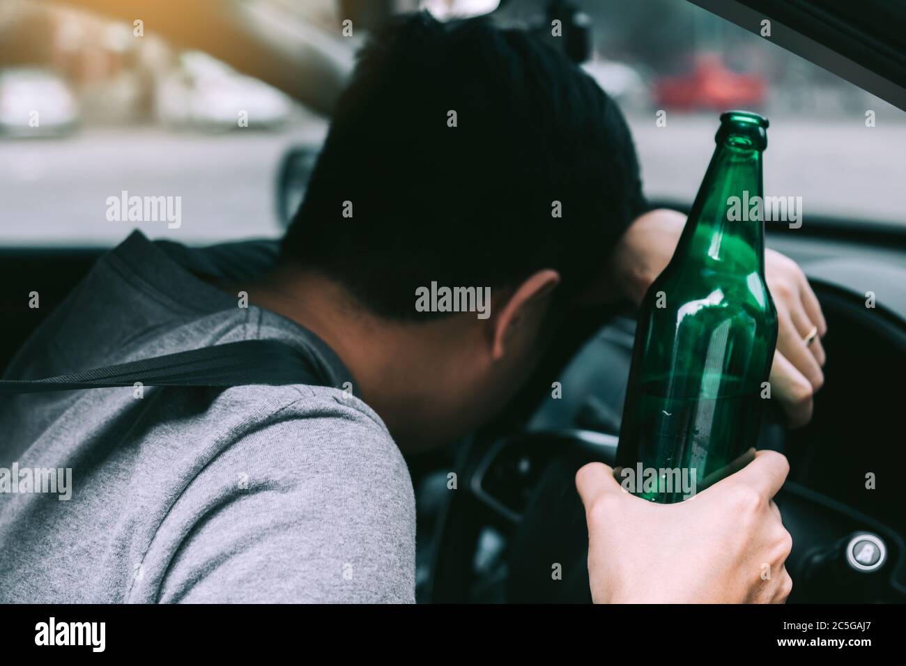 Asian men drink a lot of alcohol until and unconscious his can't drive home and decide to sleep at the steering wheel. Stock Photo