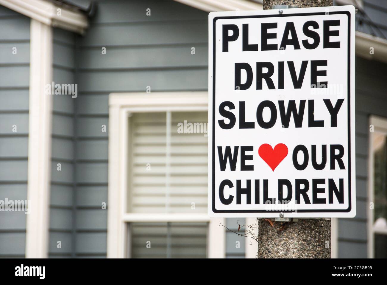 A sign on a post in a neighborhood in Mission Viejo, California stating, 'Please Drive Slowly. We Love Our Children.' Stock Photo