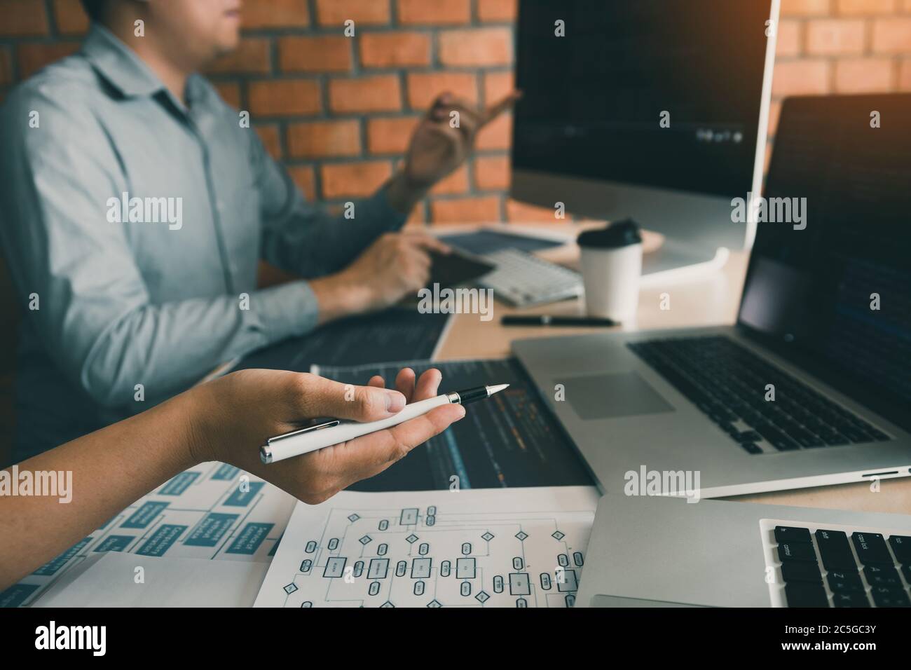 Two software developers are analyzing together about the code written into the program on the computer. Stock Photo