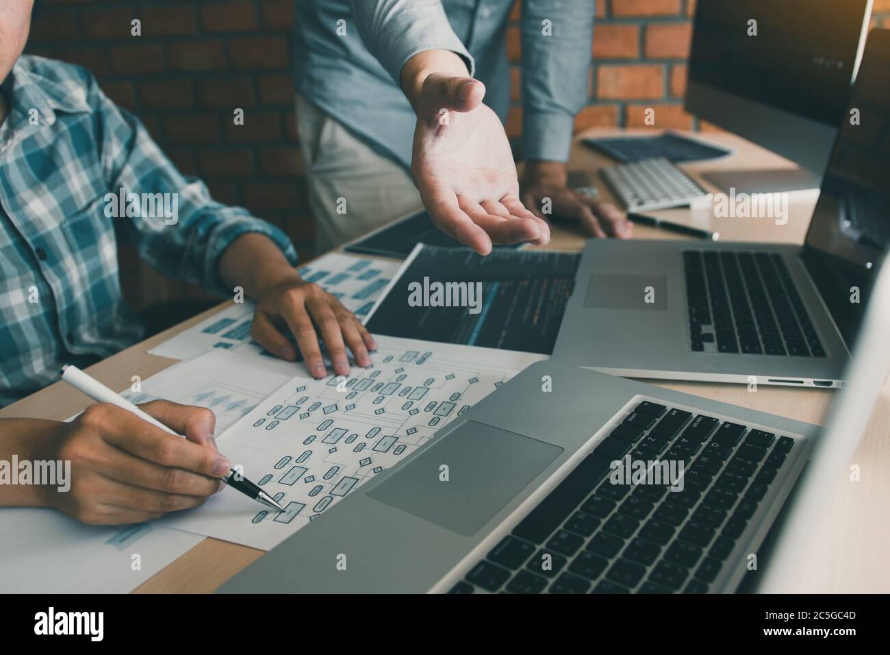 Two software developers are analyzing together about the code written into the program on the computer. Stock Photo