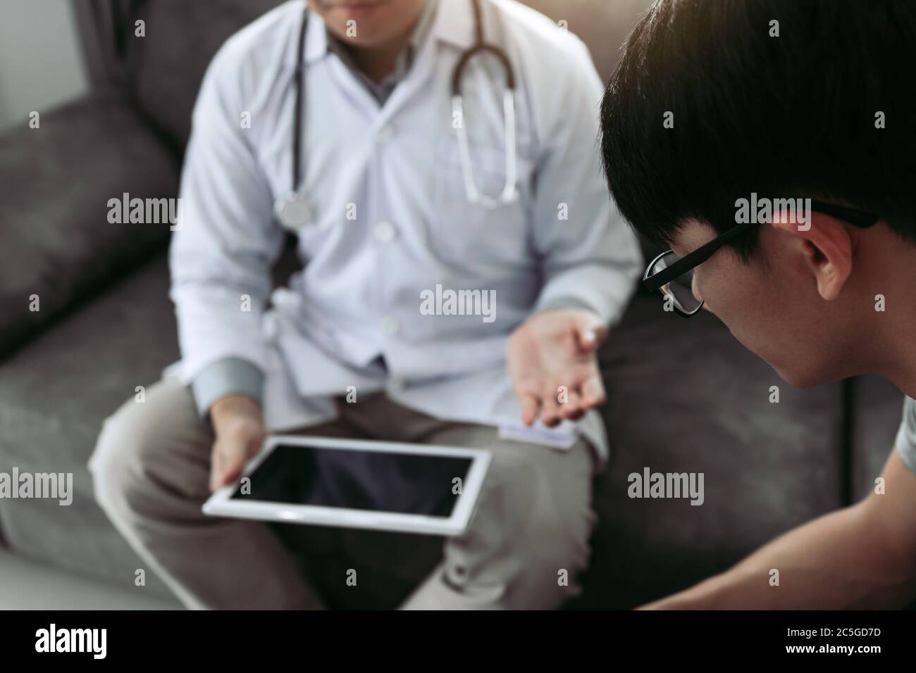 Asian doctor visited the patient at home while using the tablet ...