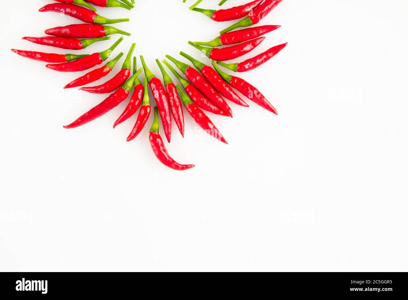 Background of red ripe Thai peppers arranged in a circle with white background and copy space. Stock Photo