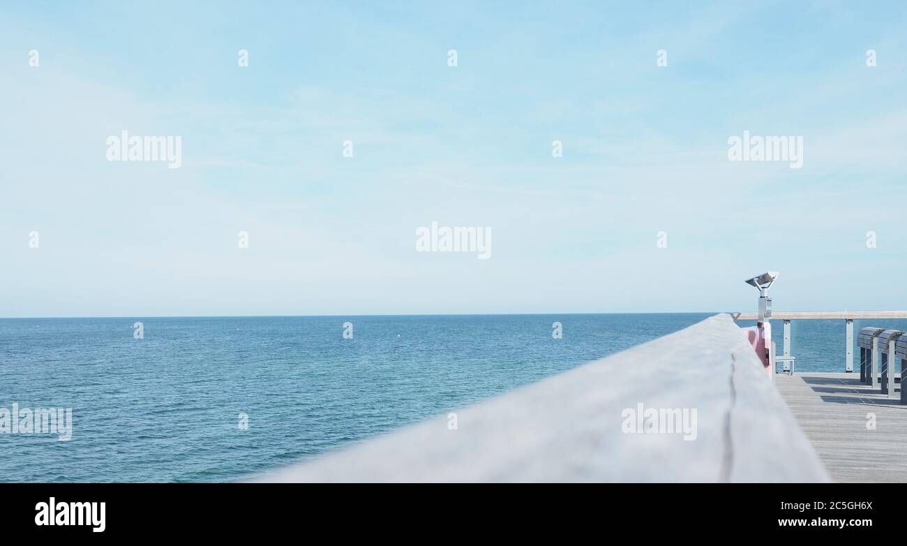 Binoculars on a pier, concept for far-sightedness or look into the future, space for text on the left Stock Photo