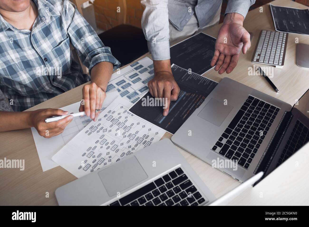 Two software developers are analyzing together about the code written into the program on the computer. Stock Photo