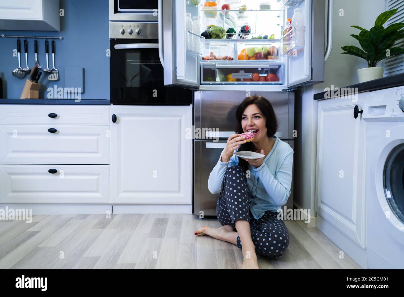 Open Night Sweet Indulgence. Woman Eating Near Refrigerator Stock Photo
