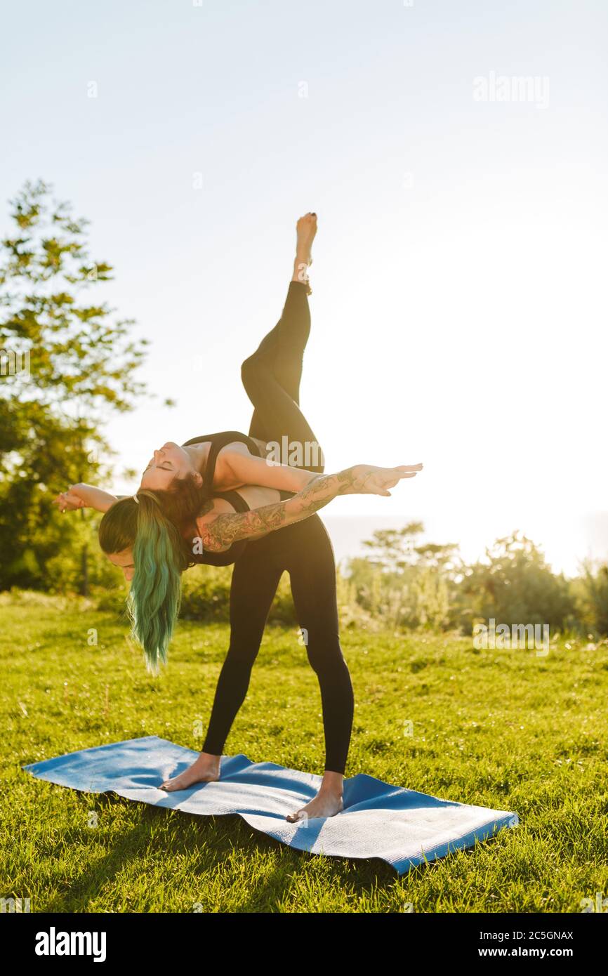 Two ladies in black sporty tops and leggings training yoga poses