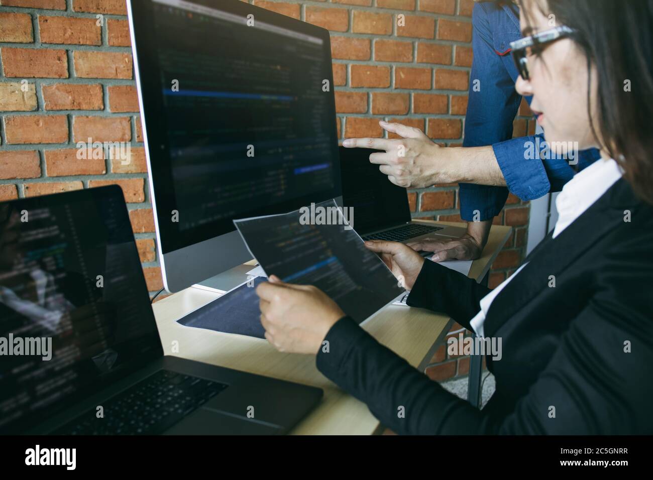 Two software developers are analyzing together about the code written into the program on the computer. Stock Photo