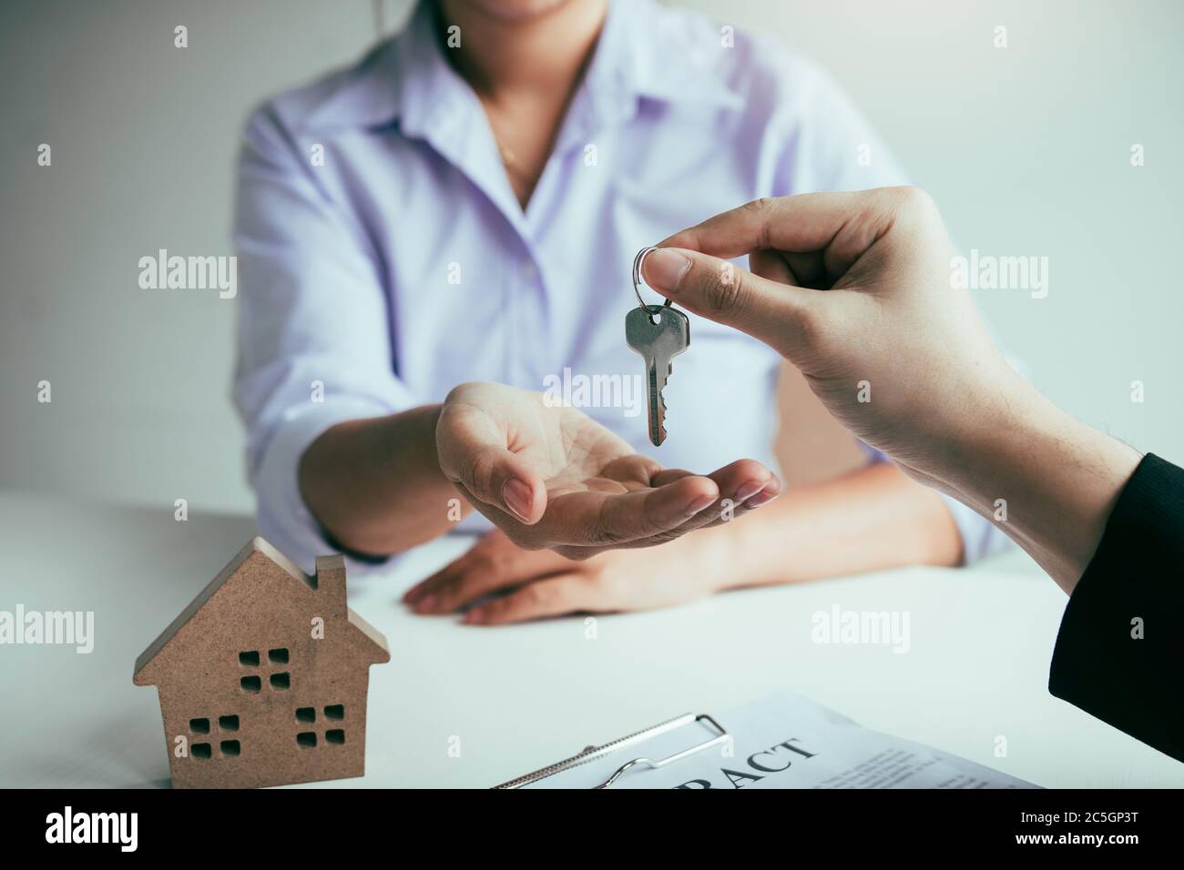 Hand of real estate agent passes the key to new homeowners in office