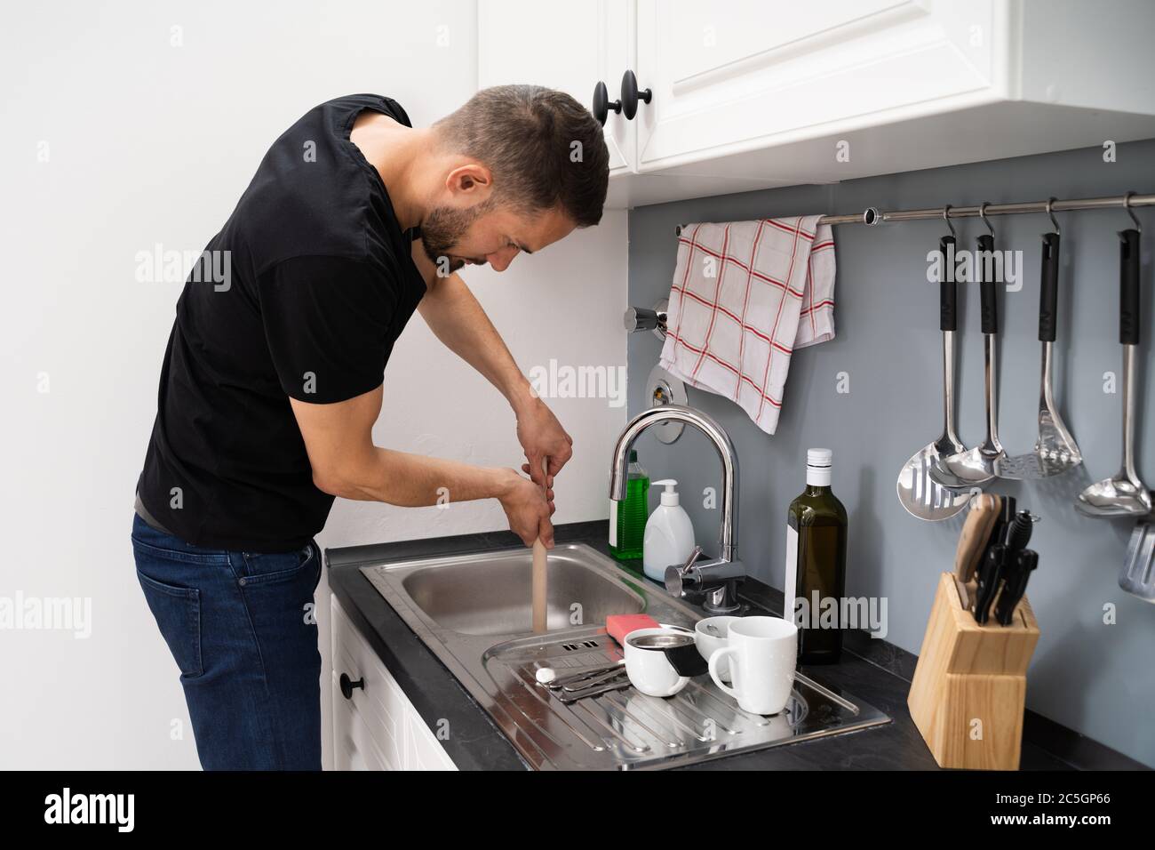 Cleaning Blocked Drain Clog In Kitchen Sink Using Plunger Stock Photo