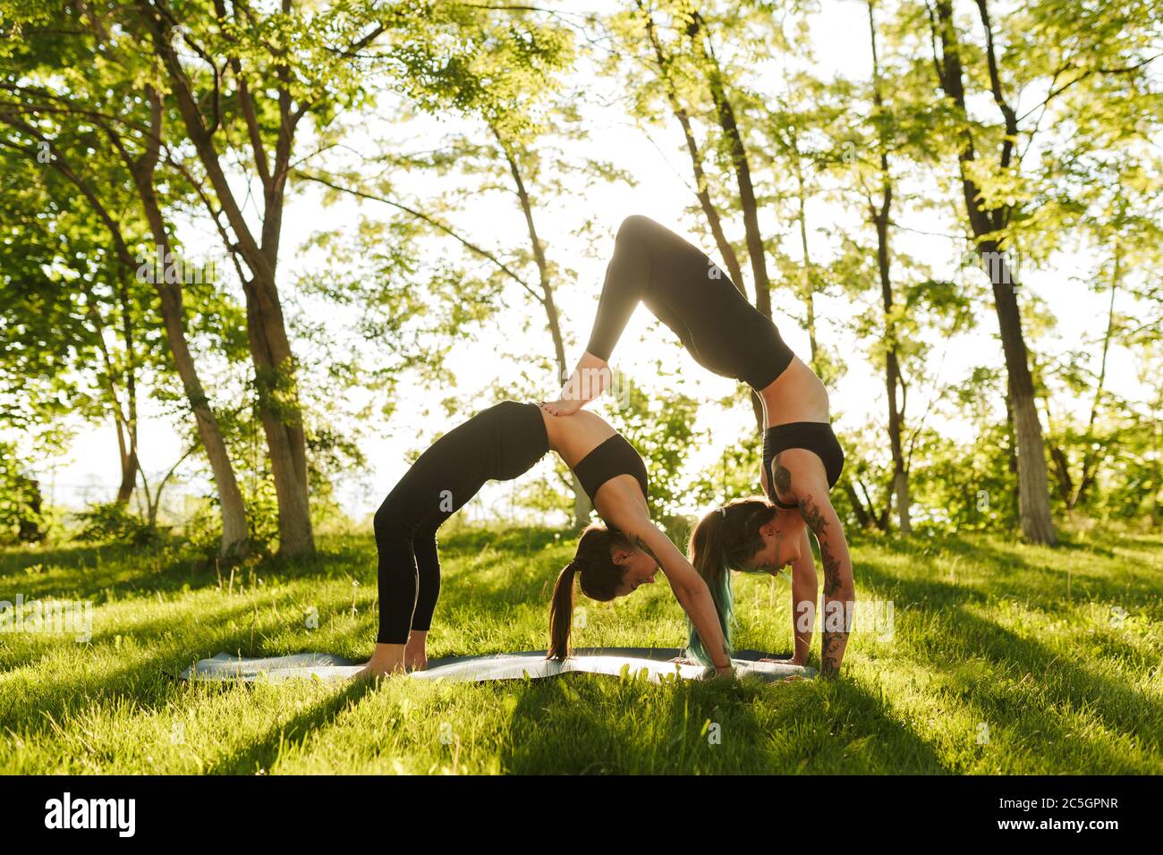 Photo Two Ladies Black Sporty Tops Leggings Training Yoga Poses Stock Photo  by ©Garetsworkshop 201307722