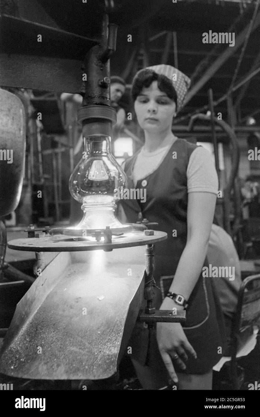 young female worker operating machine while working in glass factory 1970s salgotarjan hungary Stock Photo