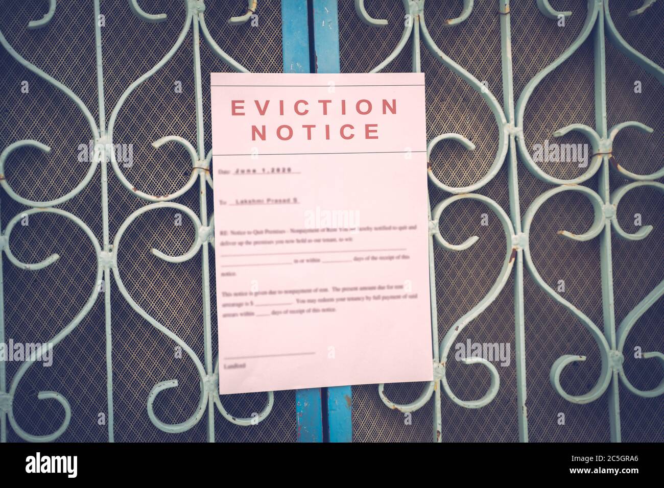 Foreclosed or eviction notice on a main door with blurred details of a house with vintage filter. Stock Photo