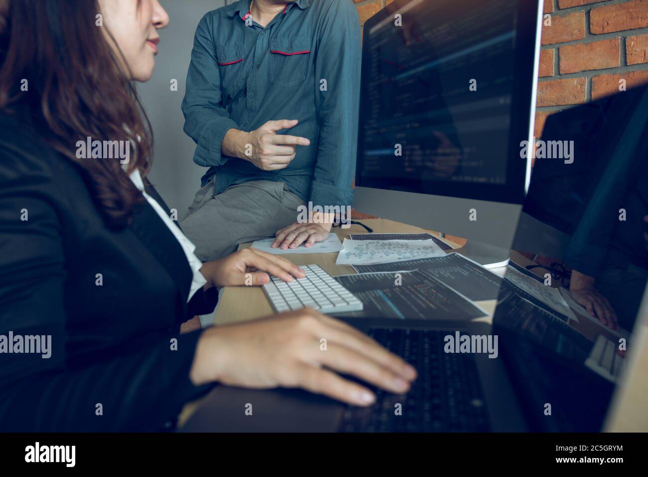 Two software developers are analyzing together about the code written into the program on the computer. Stock Photo
