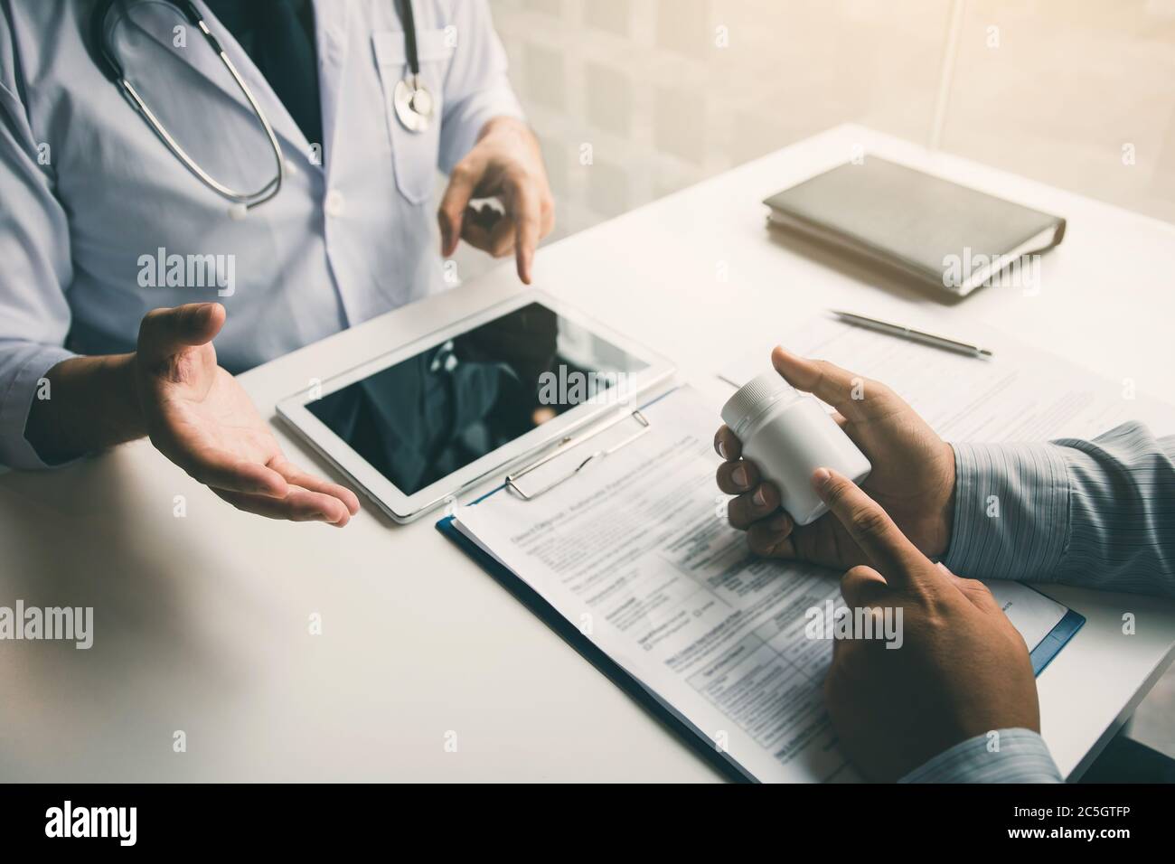 Asian doctor talking the patient at clinic while using the tablet ...