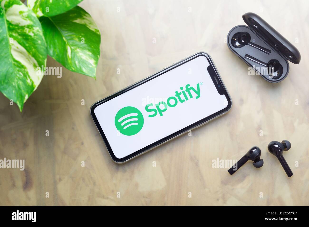 Bangkok, Thailand - July 3, 2020: Apple Iphone 11  with Spotify logo on display, bluetooth headphones with case, green plant on working table backgrou Stock Photo